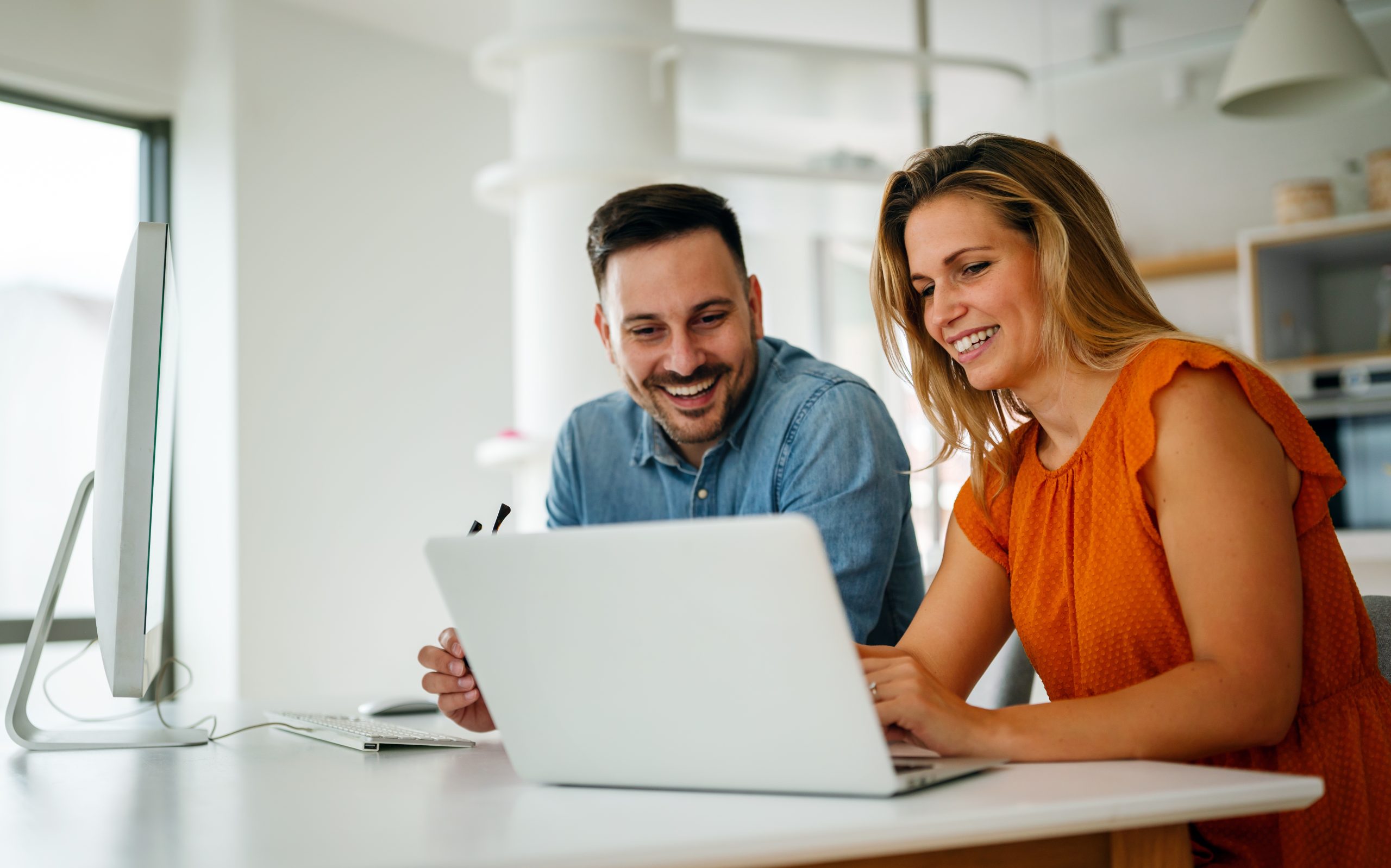 Smiling colleagues working together on a laptop