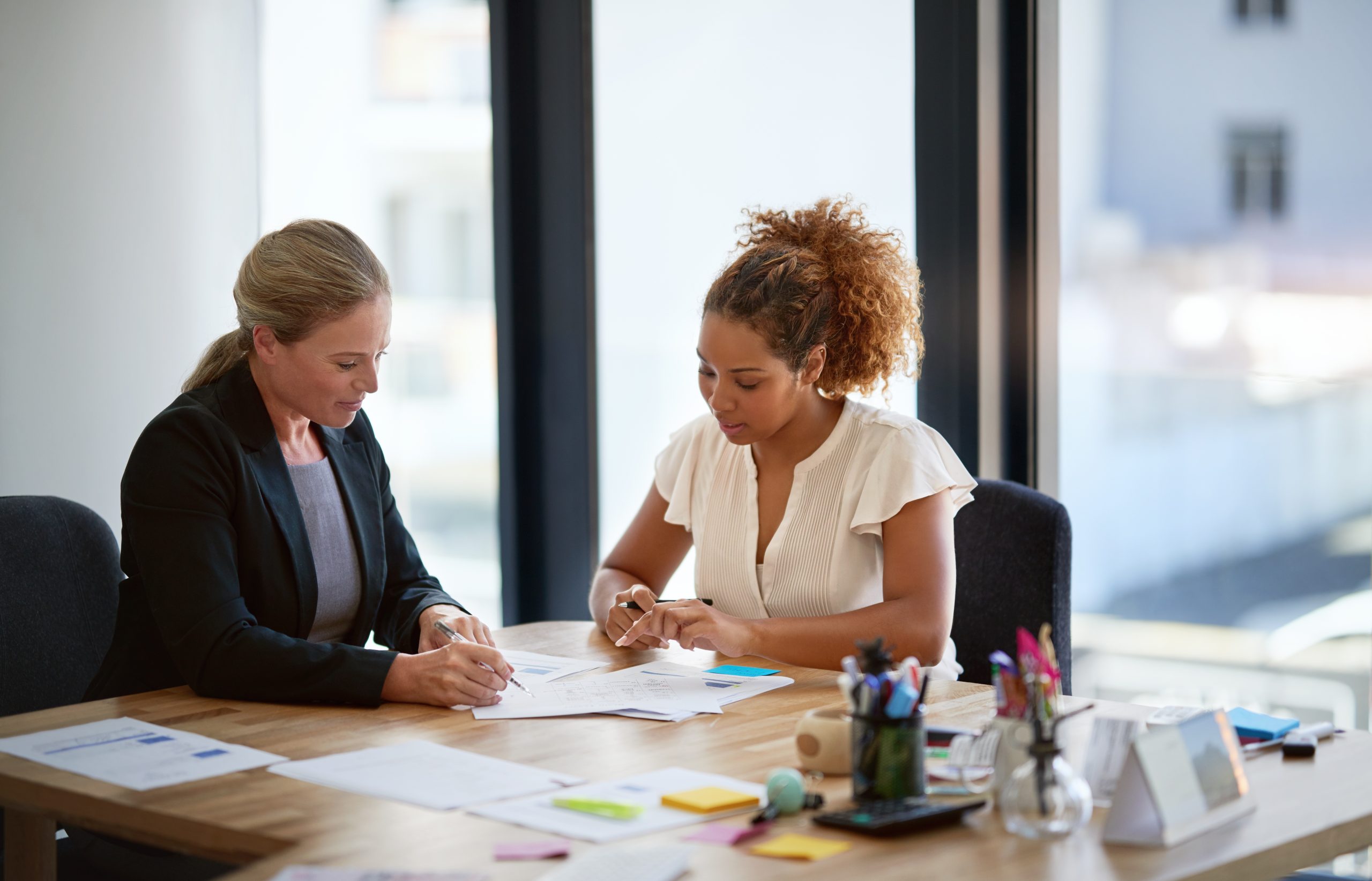 Two women discussing documents at a desk.